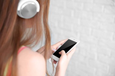 Kız akıllı telefon ve kulaklık ile müzik dinlemek
