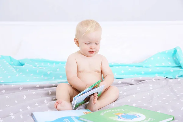 Baby with book on bed — Stock Photo, Image