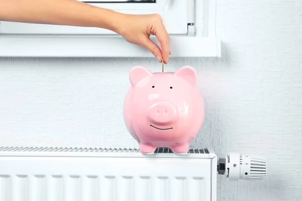 Woman hand putting money into piggy bank — Stock Photo, Image