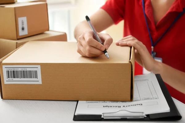 Courier writing on cardboard box — Stock Photo, Image