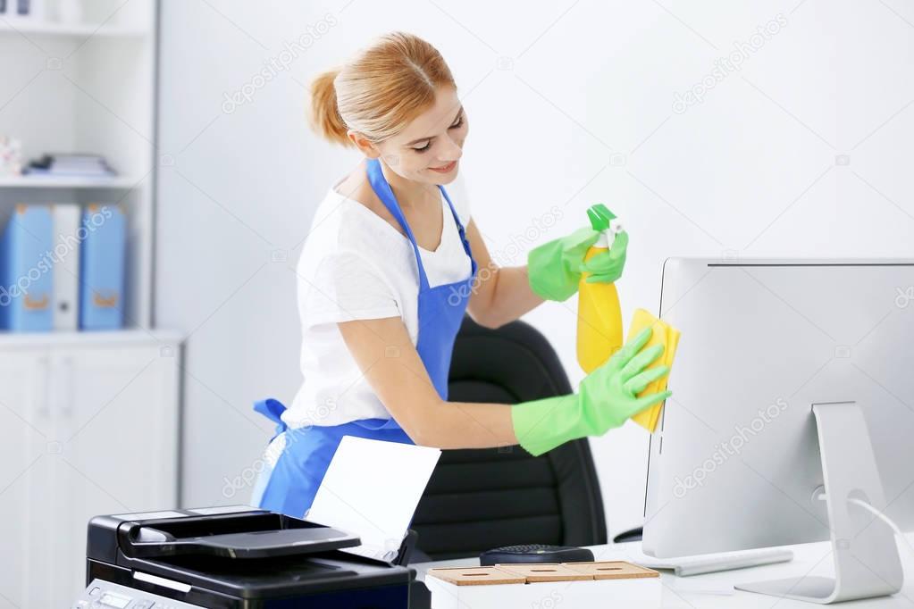 woman wiping computer in office