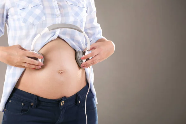 Mujer embarazada con auriculares en la barriga — Foto de Stock