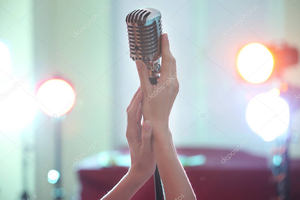 Female hands holding retro microphone