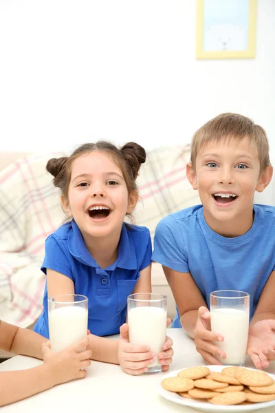Happy children with glasses of milk at table