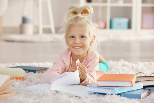 Niña con muchos libros sobre alfombra —  Fotos de Stock