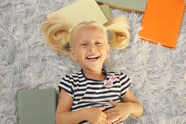 Niña con un montón de libros en la alfombra, vista superior —  Fotos de Stock