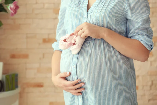 Wanita memegang bootees bayi di perut — Stok Foto