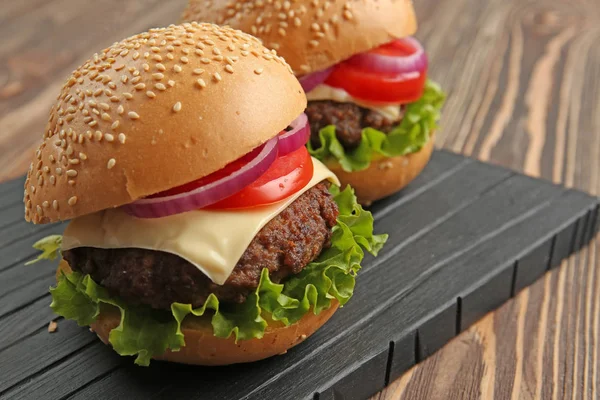 Delicious cheeseburgers on wooden table — Stock Photo, Image