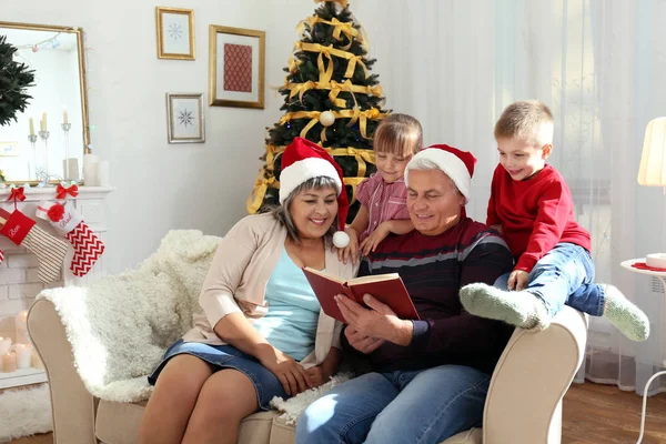 Starší Pár Čítanka Jejich Vnoučata Obývacím Pokoji Zdobené Vánoce — Stock fotografie