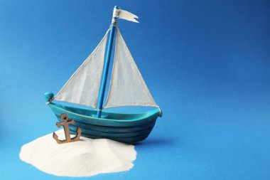 Ahşap tekne, çapa ve kum mavi arka plan üzerinde. Kolomb Günü kavramı
