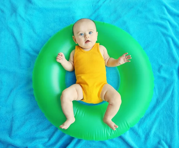 Lindo bebé con anillo de natación acostado sobre una colcha azul . — Foto de Stock