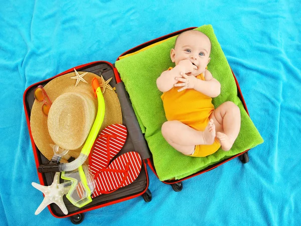 Söt baby och saker för semester i resväska liggande på Blå överkast. — Stockfoto