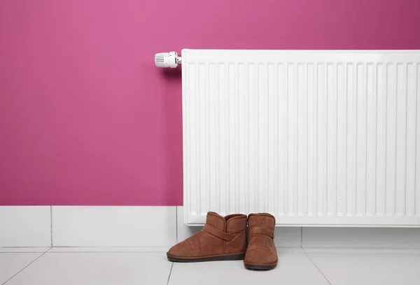 Shoes standing near heating radiator — Stock Photo, Image