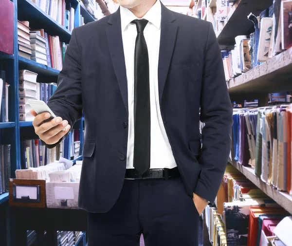 Hombre con teléfono en la biblioteca, primer plano — Foto de Stock