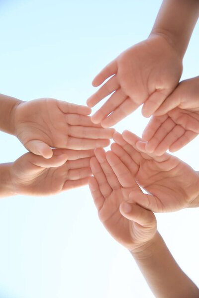 Children hands against blue sky, close up