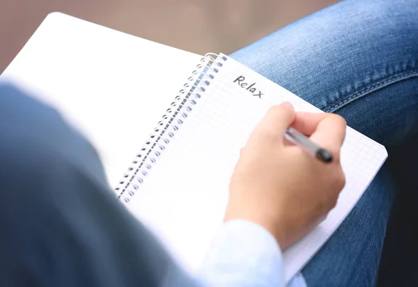 Jeune femme écrivant mot "relax" dans le carnet — Photo