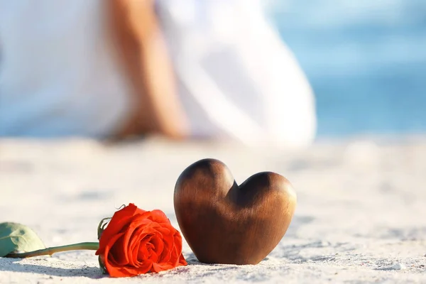 Rote Rose mit dekorativem Herz auf Sand — Stockfoto