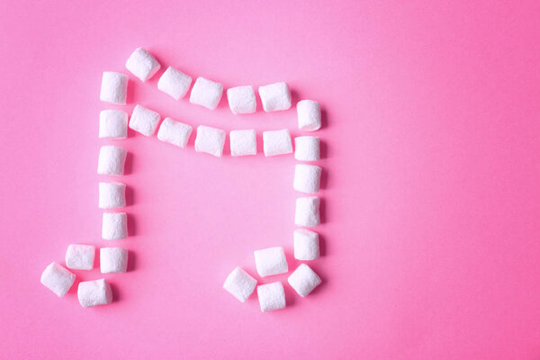 Musical note made of marshmallow on pink background