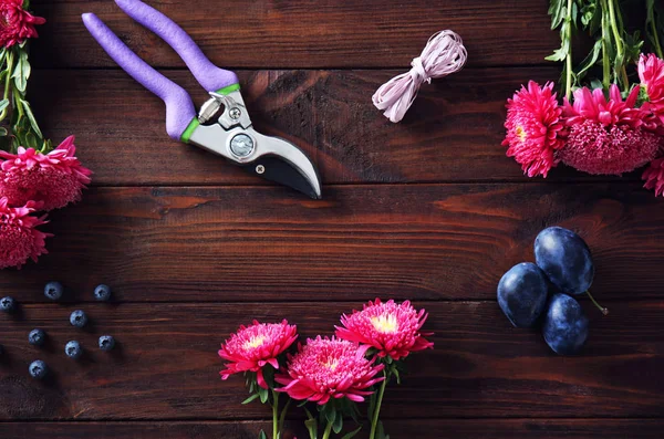 Vackra blommor med sekatör och plommon — Stockfoto