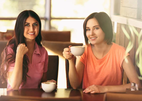 Alegres mujeres jóvenes tomando café en la cafetería en un día soleado —  Fotos de Stock