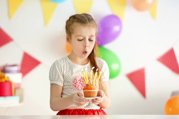 Милая маленькая девочка задувает свечи — стоковое фото