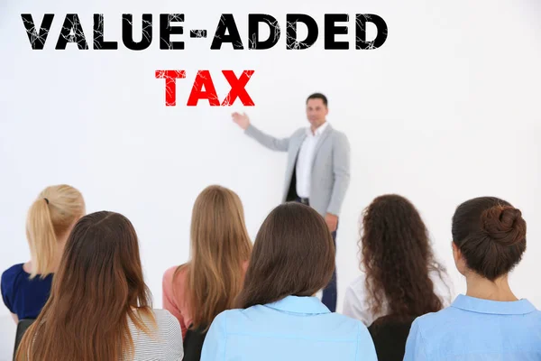 Tax concept. Business people at conference. Text VALUE-ADDED TAX on background