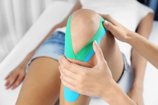 Female knee with physio tape — Stock Photo, Image