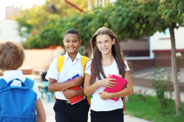 Öğrenciler sırt çantaları ve sokakta yürürken dizüstü bilgisayarlar ile