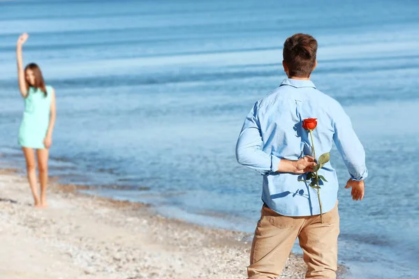 Молодой человек прячет красную розу — стоковое фото