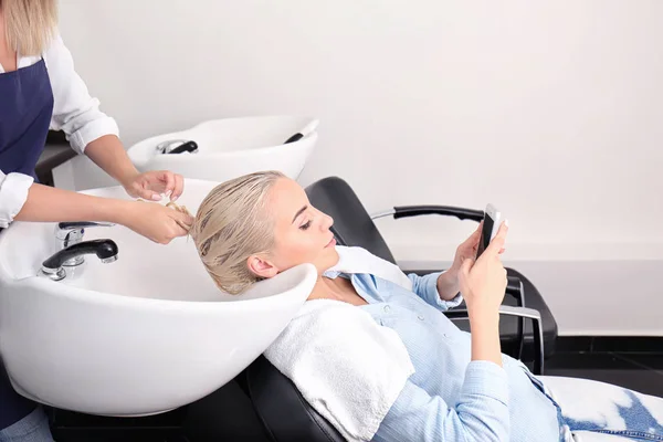 Hairdresser washing woman's hair — Stock Photo, Image