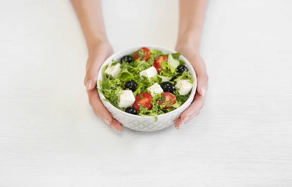 Handen met kom met salade — Stockfoto