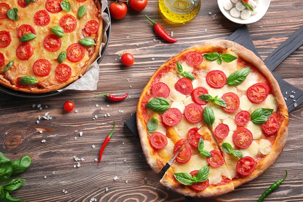 Delicious pizzas on kitchen table — Stock Photo, Image