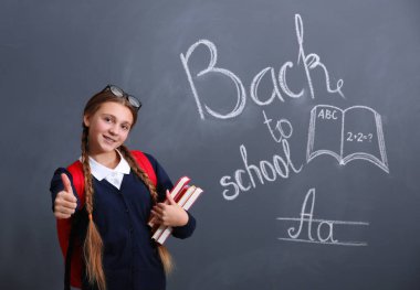 Sırt çantası ve okul blackboard duran kitaplar ile kız