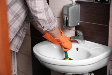 Plumber repairing sink with hand plunger, closeup clipart