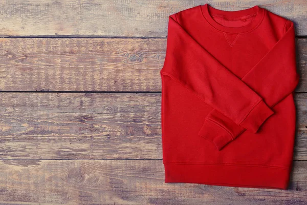 Camisola vermelha quente no fundo de madeira — Fotografia de Stock