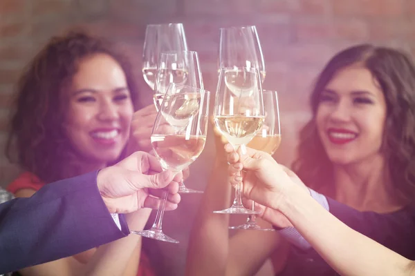 People toasting with glasses of white wine, closeup