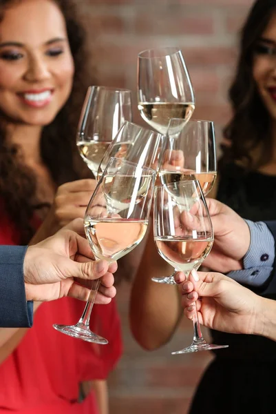 People toasting with glasses of white wine, closeup