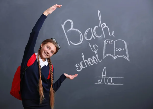 Girl with backpack near blackboard — Stock Photo, Image