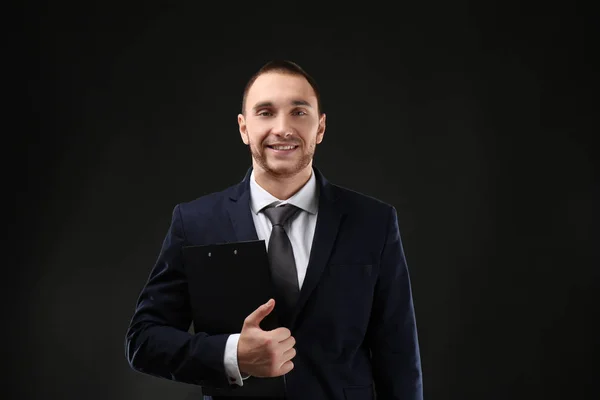 Jonge business coach met Klembord staan op zwarte achtergrond — Stockfoto