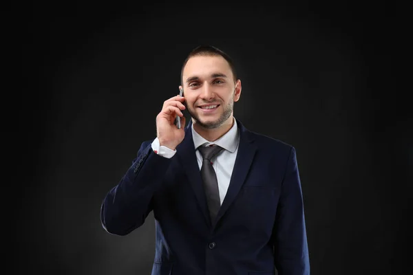 Молодий бізнес-тренер розмовляє мобільним телефоном на чорному фоні — стокове фото