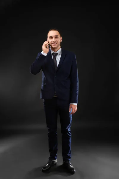 Mladí obchodní trenér mluvící mobil na černém pozadí — Stock fotografie