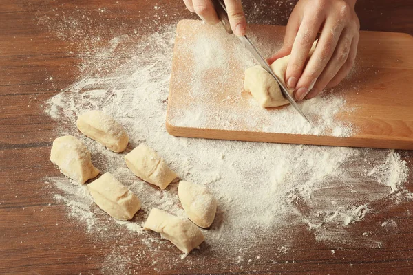 Женщина режет сырое тесто — стоковое фото