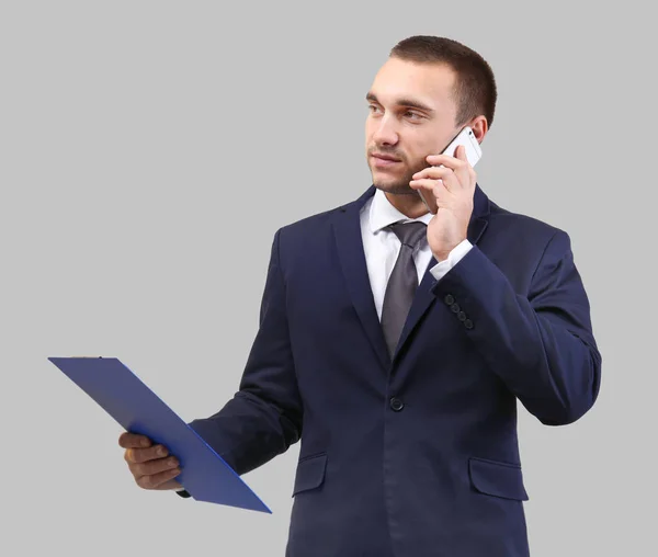 Handsome Man Holding Clipboard While Talking Mobile Phone Light Background — Stock Photo, Image