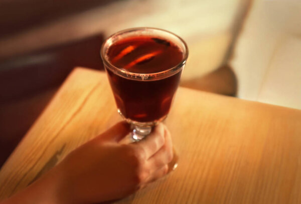 Female hand and glass of mulled wine