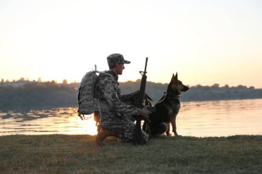Alman çoban köpeği gün batımında Nehri yakınında olan asker