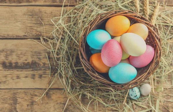 Cesta de vime com ovos de Páscoa coloridos — Fotografia de Stock