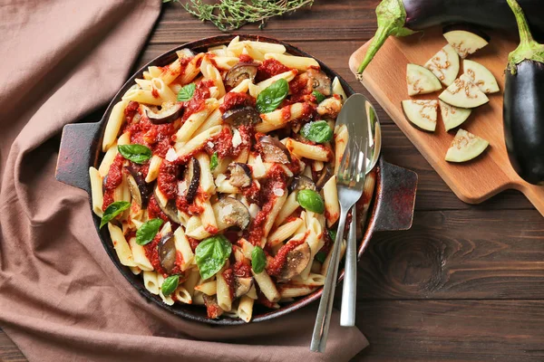 Sartén con sabrosos macarrones, servilleta, tablero de cocina y productos — Foto de Stock