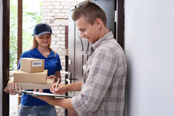 Young man receiving package from courier