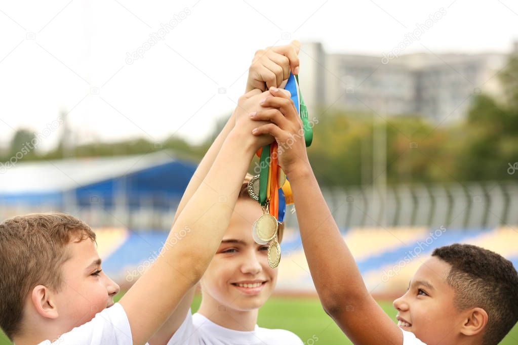 Happy winners holding medals on football field