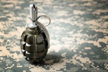 Hand grenade on camouflage clothing background clipart